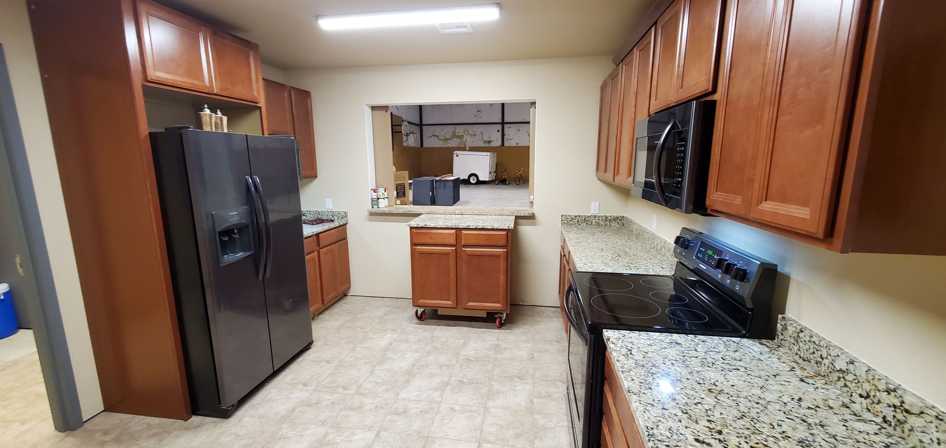 A kitchen with a refrigerator , stove , and microwave.