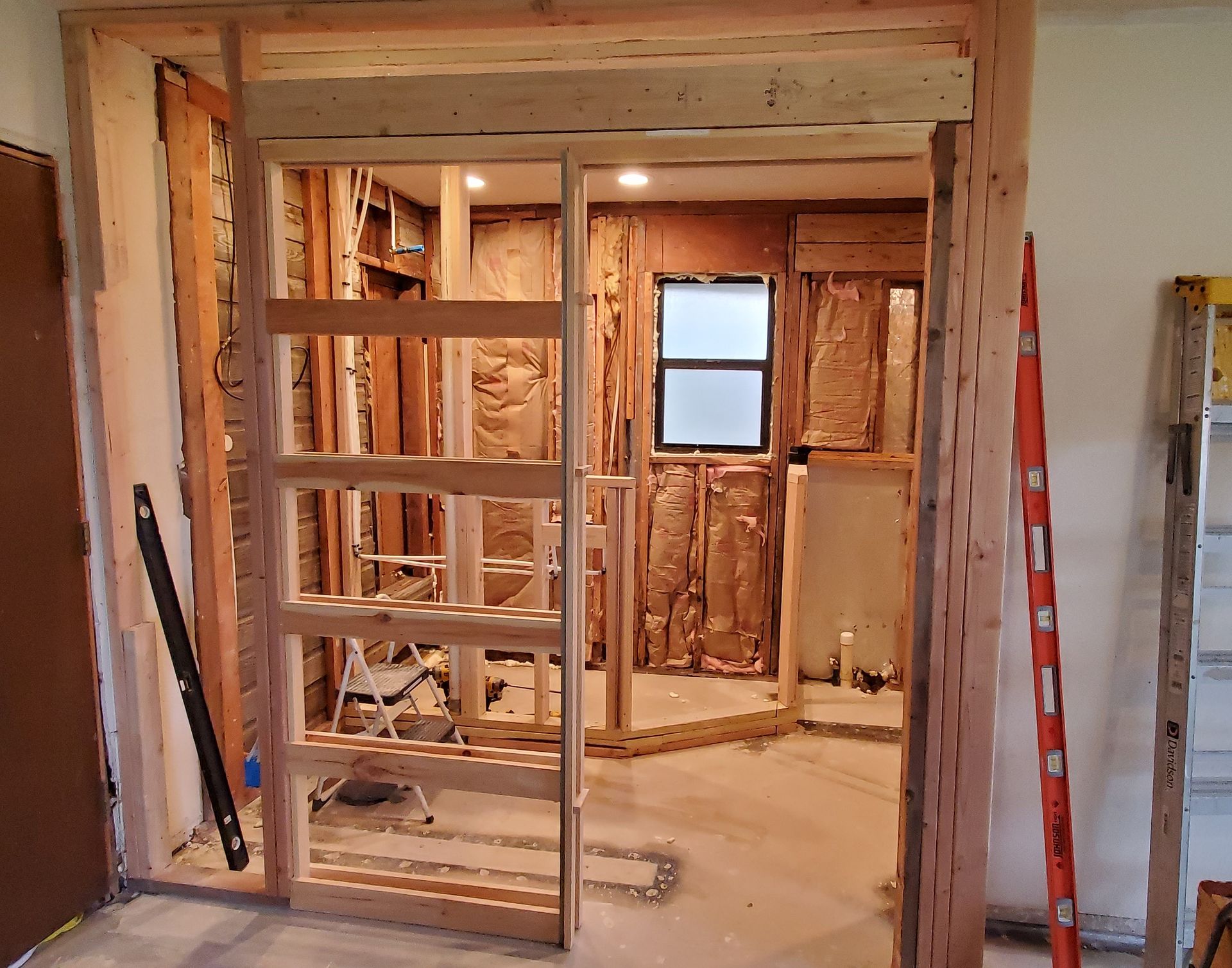 A room under construction with a ladder and a window