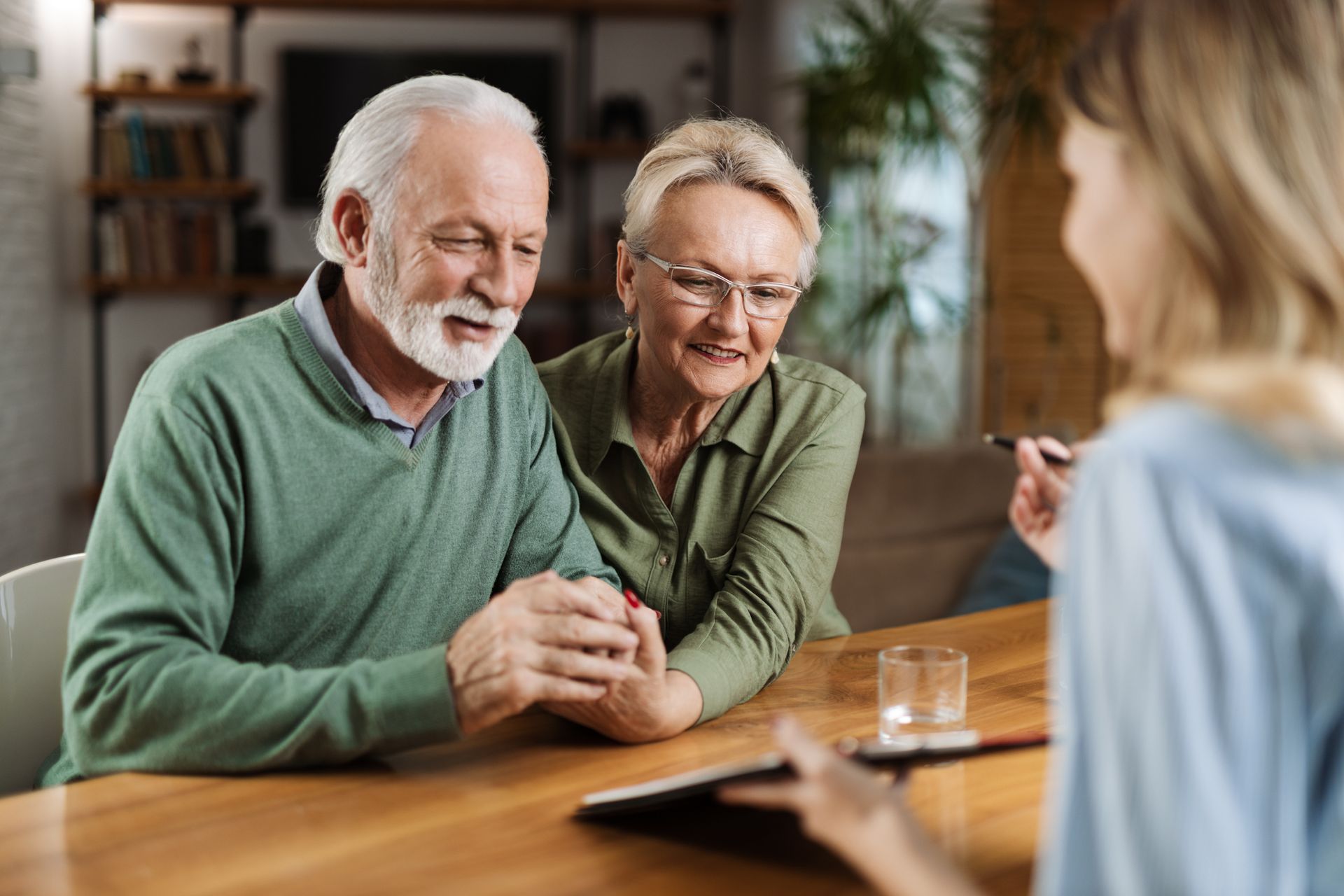 Smiling couple seated at a table, talking with a person across from them in a warm indoor setting