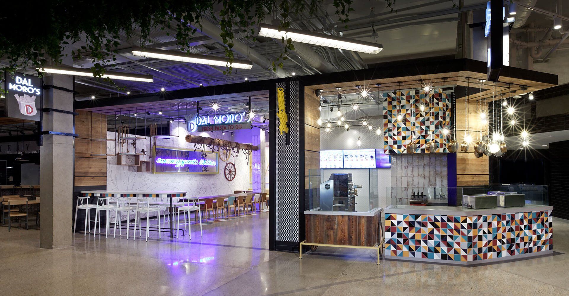 A restaurant with a purple light on the ceiling and tables and chairs.