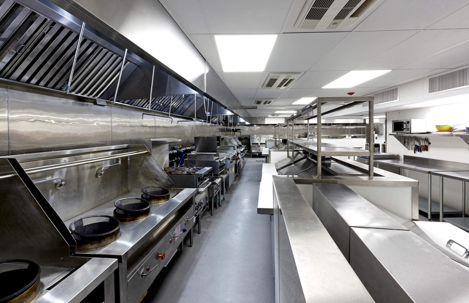 A very long kitchen with lots of stainless steel appliances