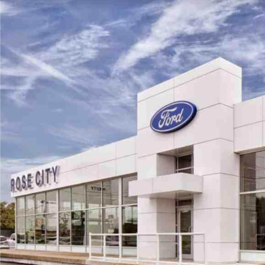 A ford dealership in rose city with a blue sky in the background