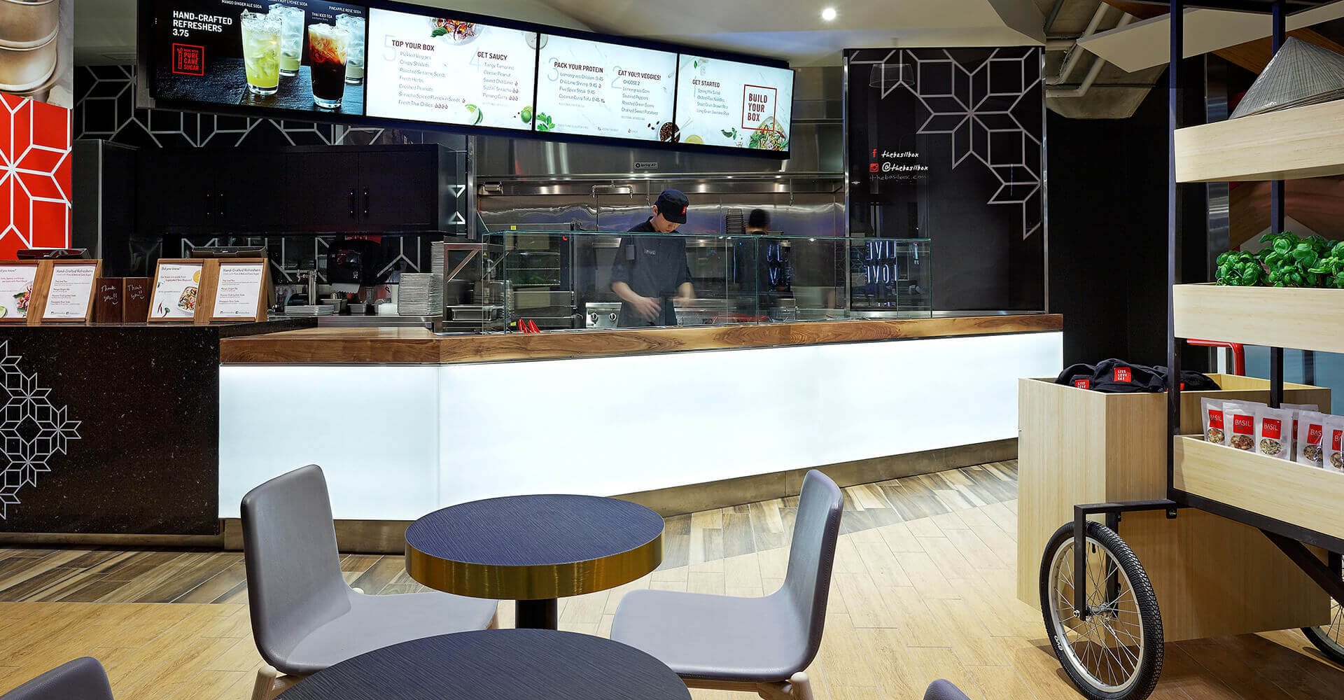 A restaurant with tables and chairs in front of a counter.