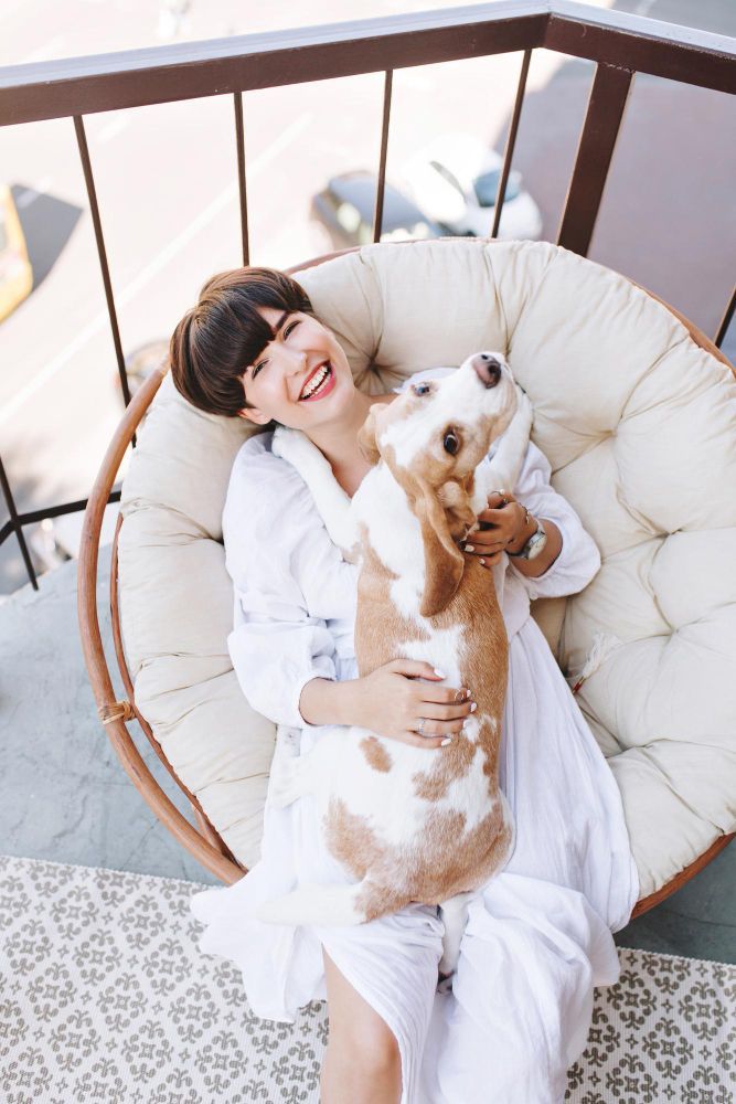 A woman is sitting in a chair holding a dog.
