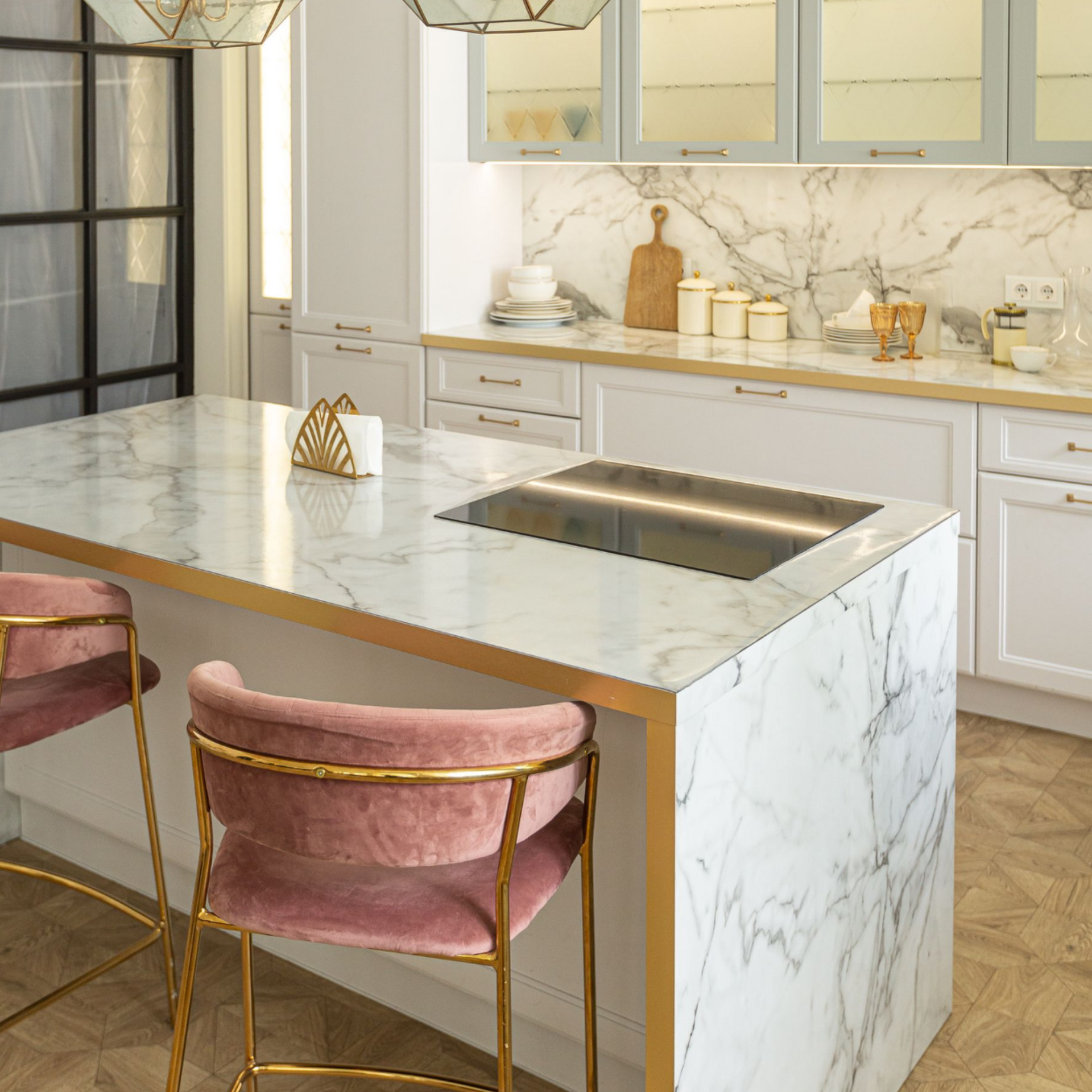 Bright modern kitchen with marble island, pink stools, and a built-in cooktop