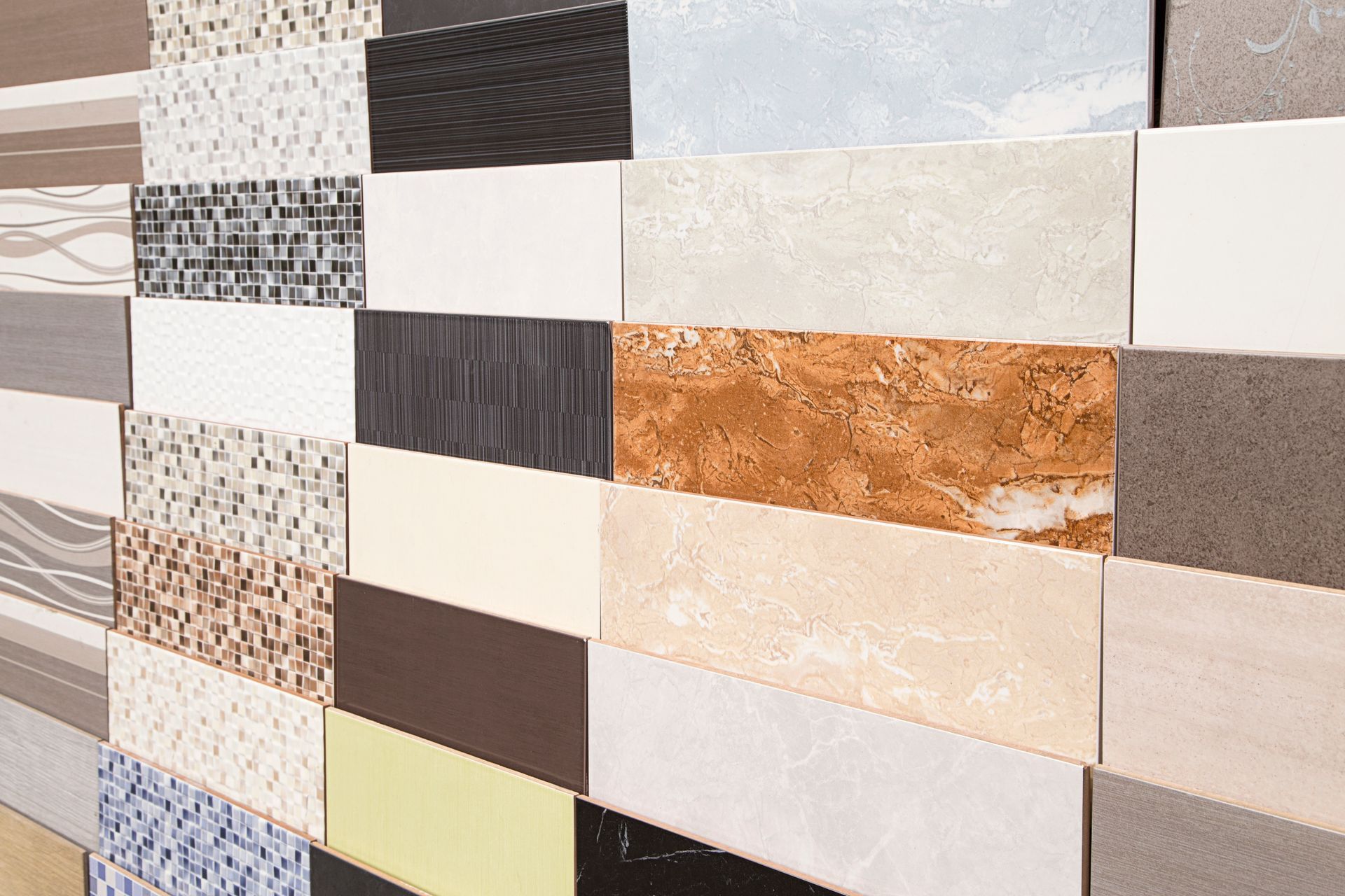 Close-up of a wall of rectangular mosaic tiles in black, white, beige, and brown tones.