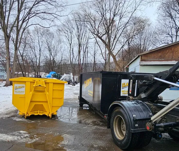 A yellow dumpster is sitting next to a black dumpster on a truck.
