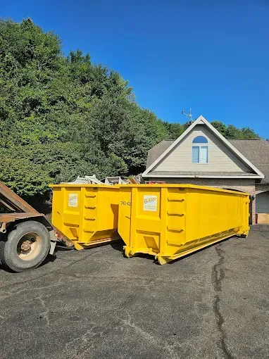 A large yellow dumpster is sitting on the side of a road.