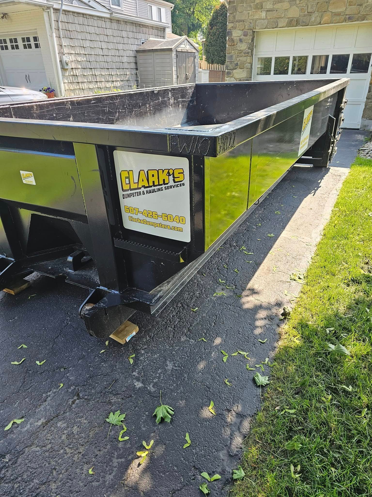 A black roll-off dumpster with a white logo for 