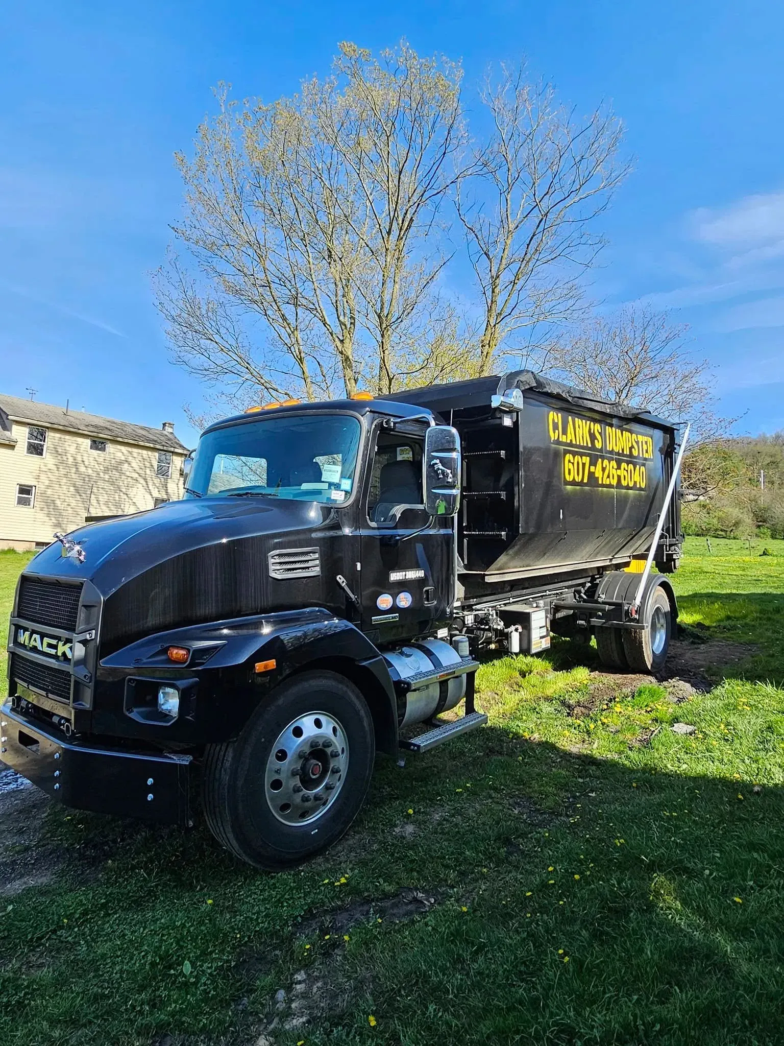 A black dump truck is parked in a grassy field.