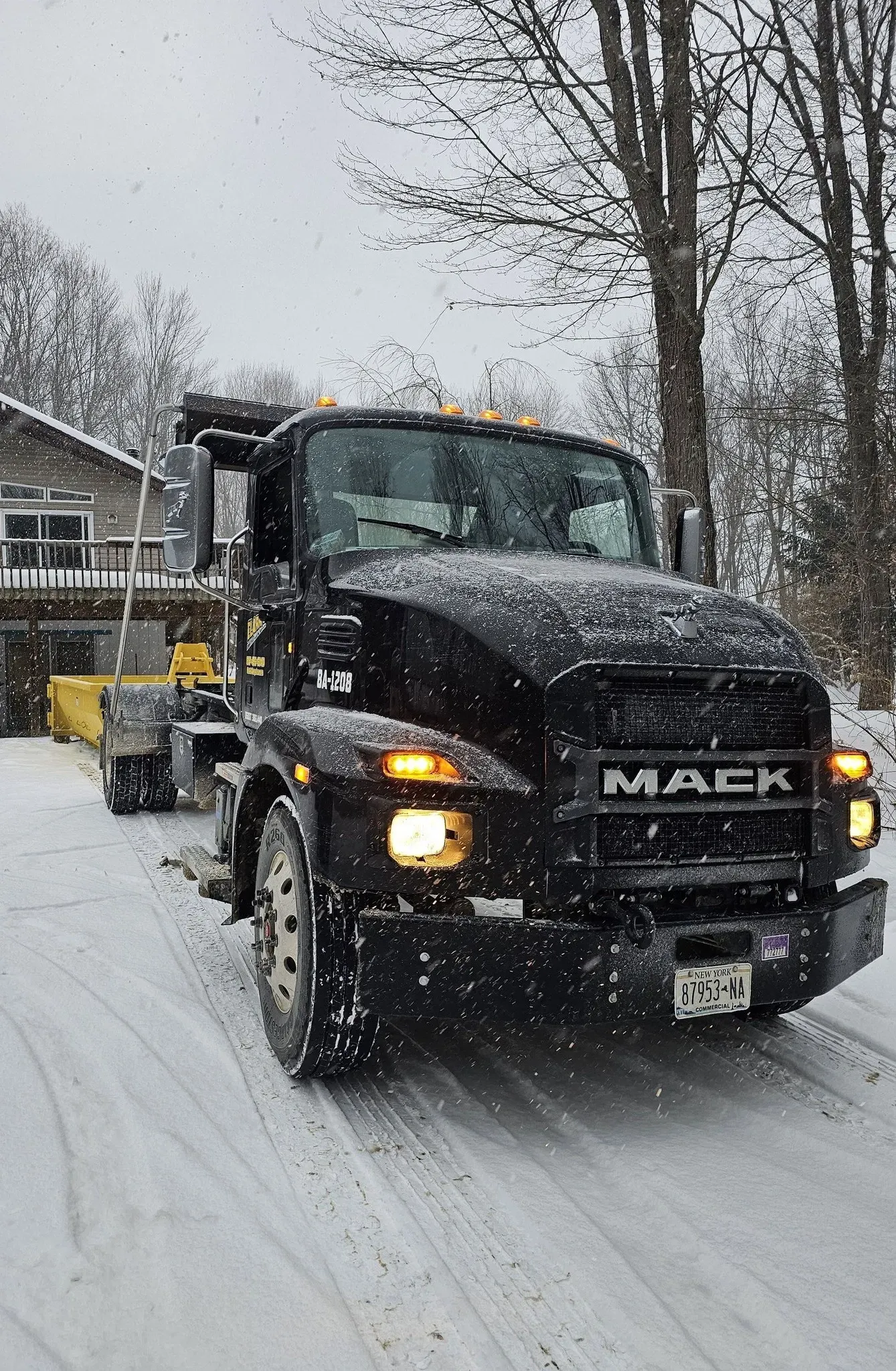 A mack truck is driving down a snowy road.