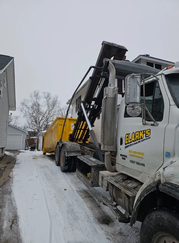 A dump truck is parked in the snow next to a house.