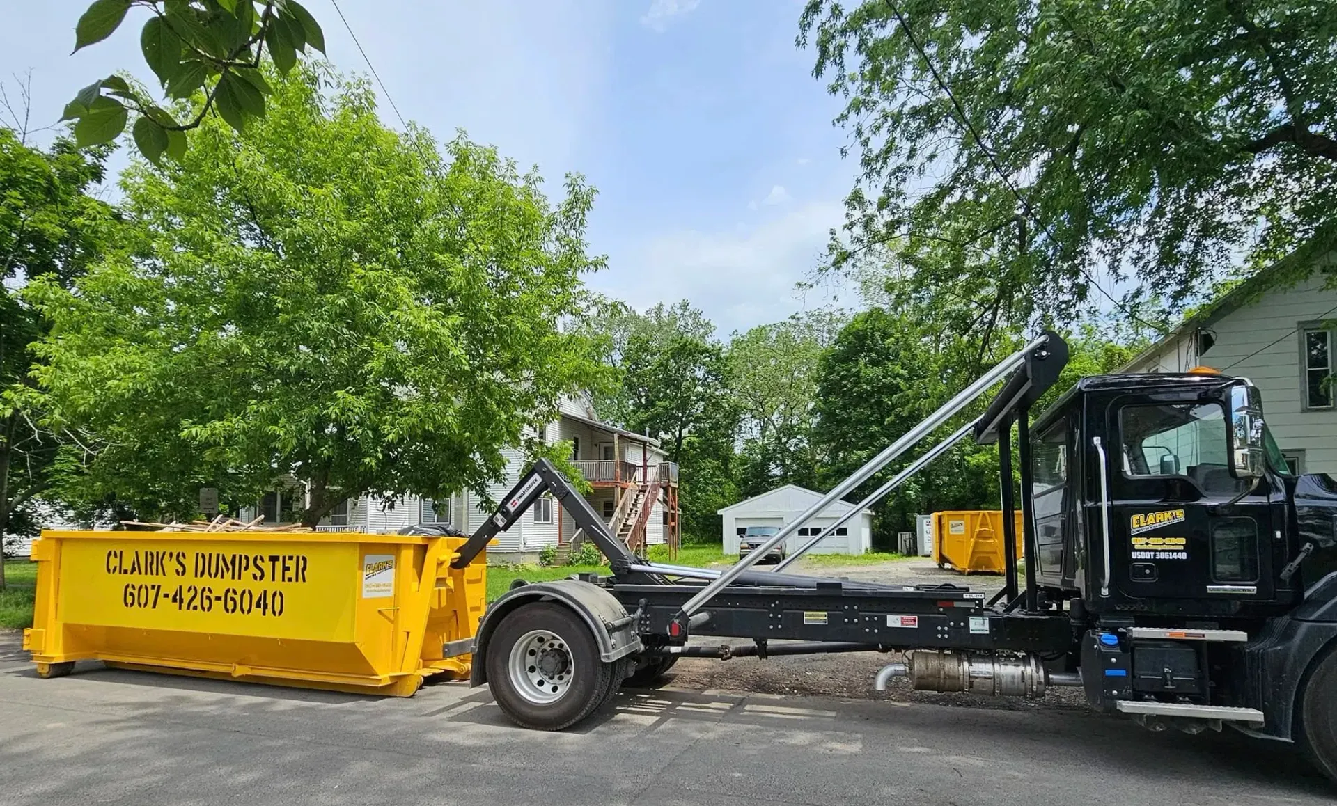 A dumpster is being loaded onto a dump truck.