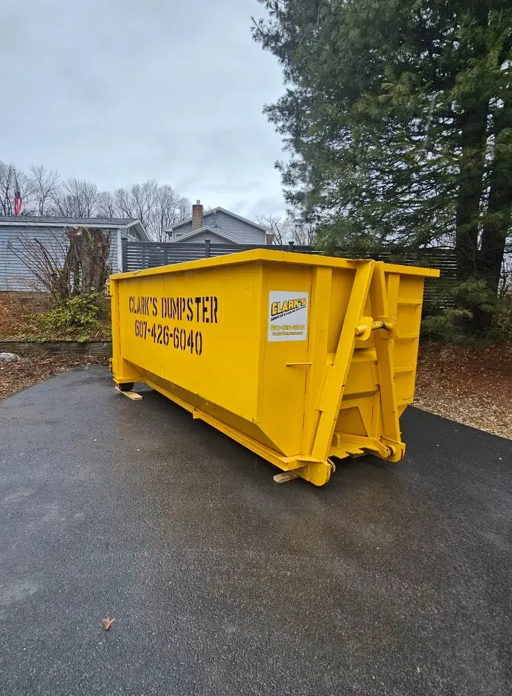 A large yellow dumpster is sitting on the side of a road.