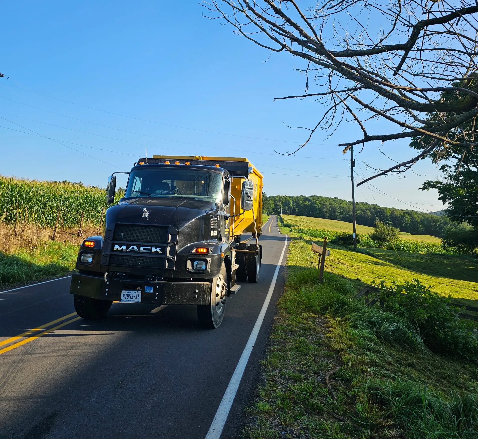 A mack truck is driving down a country road