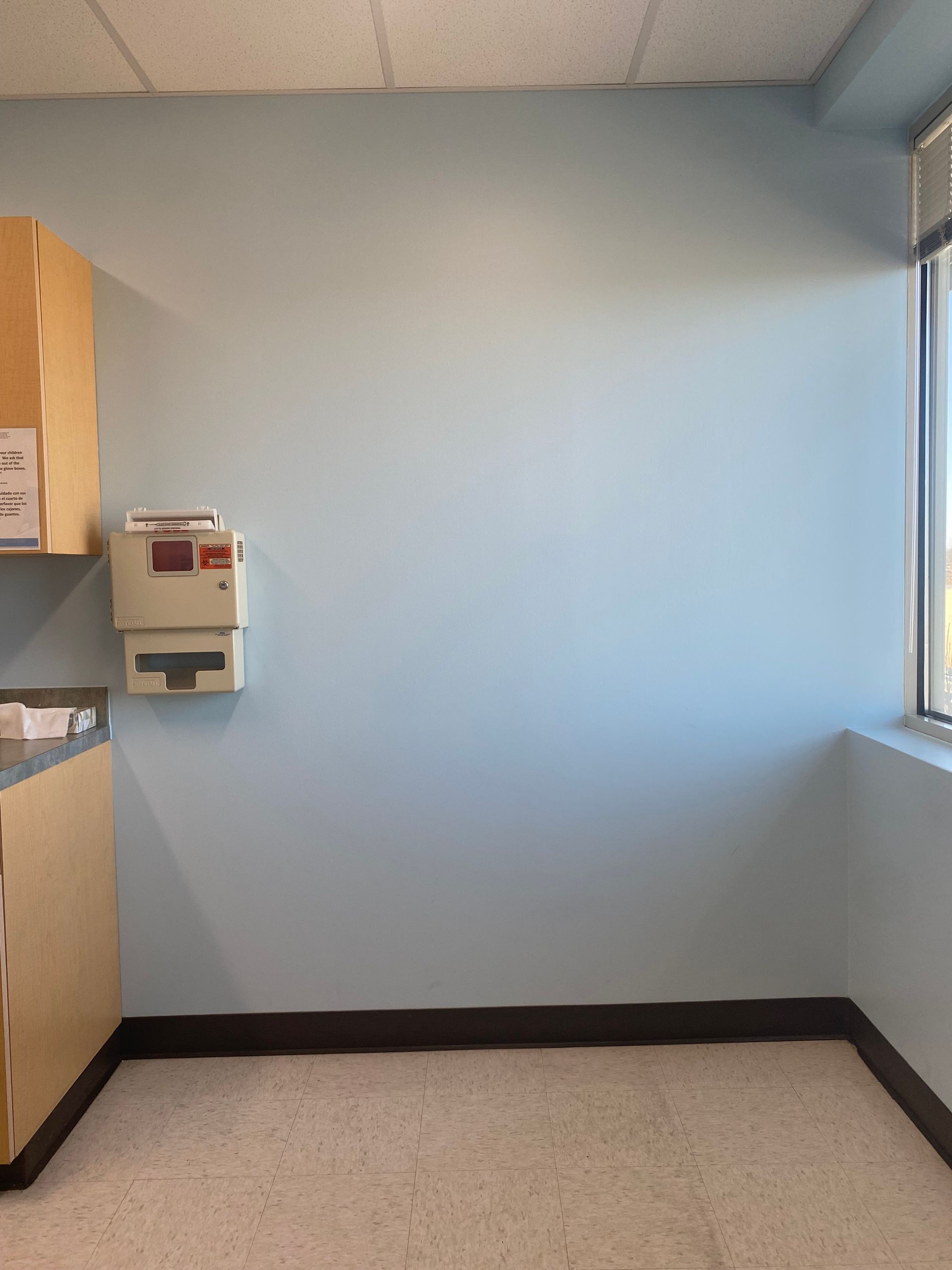 Exam room before the mural, a plain blue wall