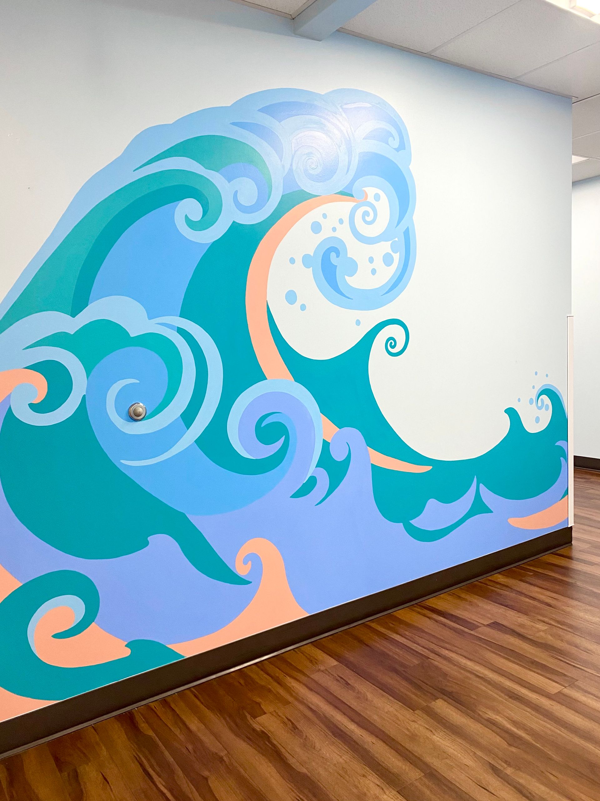 Large hand-painted ocean wave mural in a pediatric office hallway at Dell Children's, Austin TX