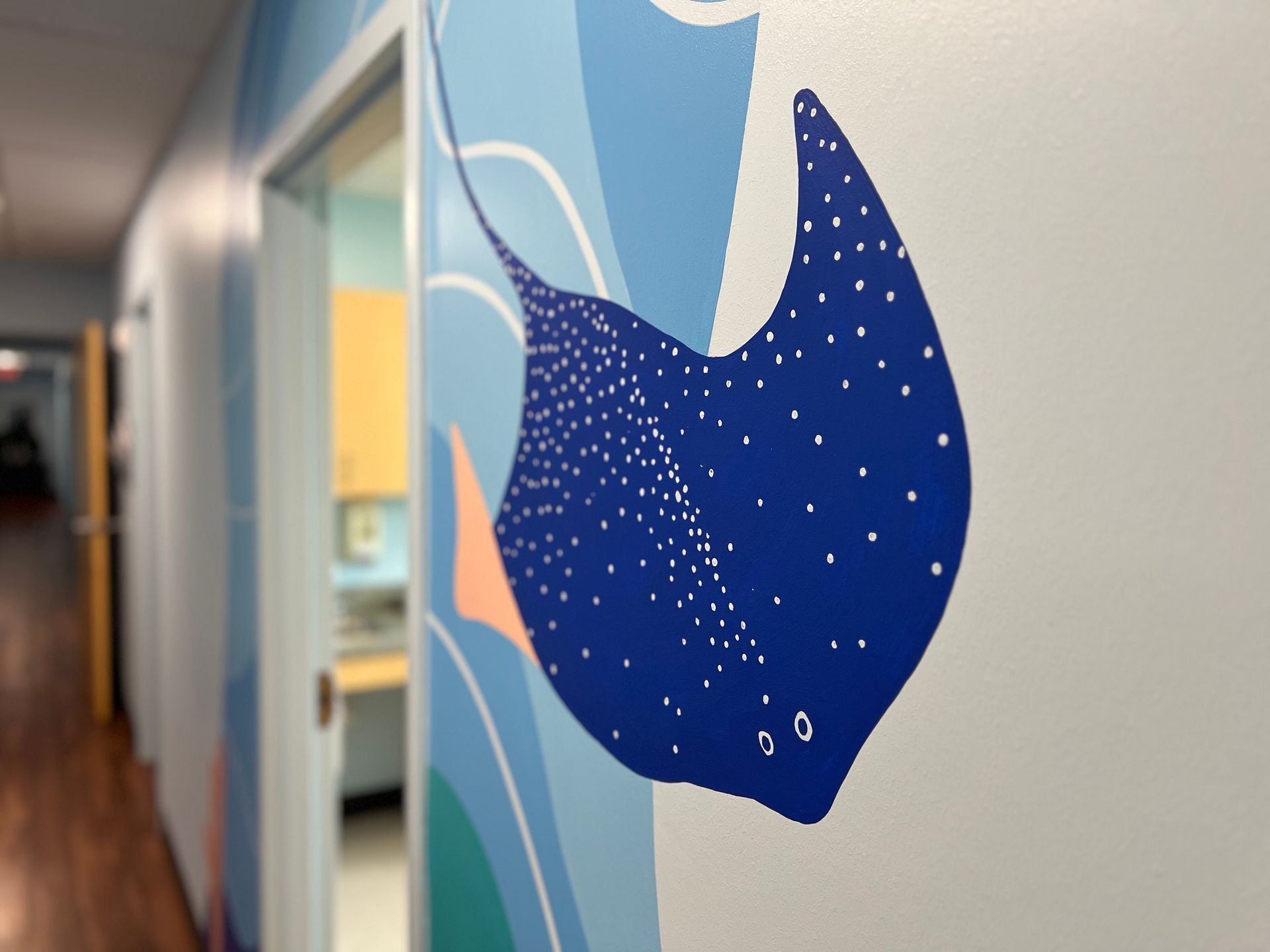 Close-up of a hand-painted stingray mural in a pediatric office hallway