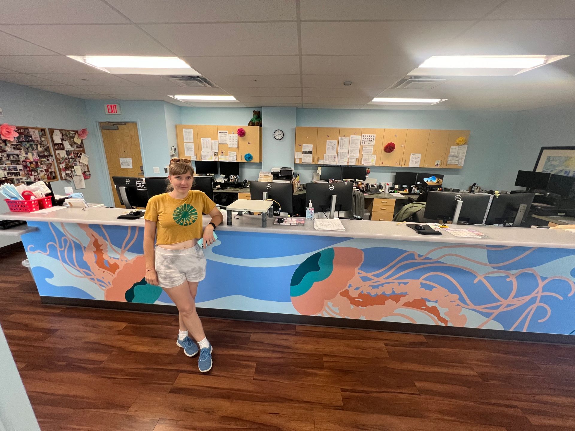 Austin muralist Becka Barbour at the jellyfish front desk mural in a pediatric office