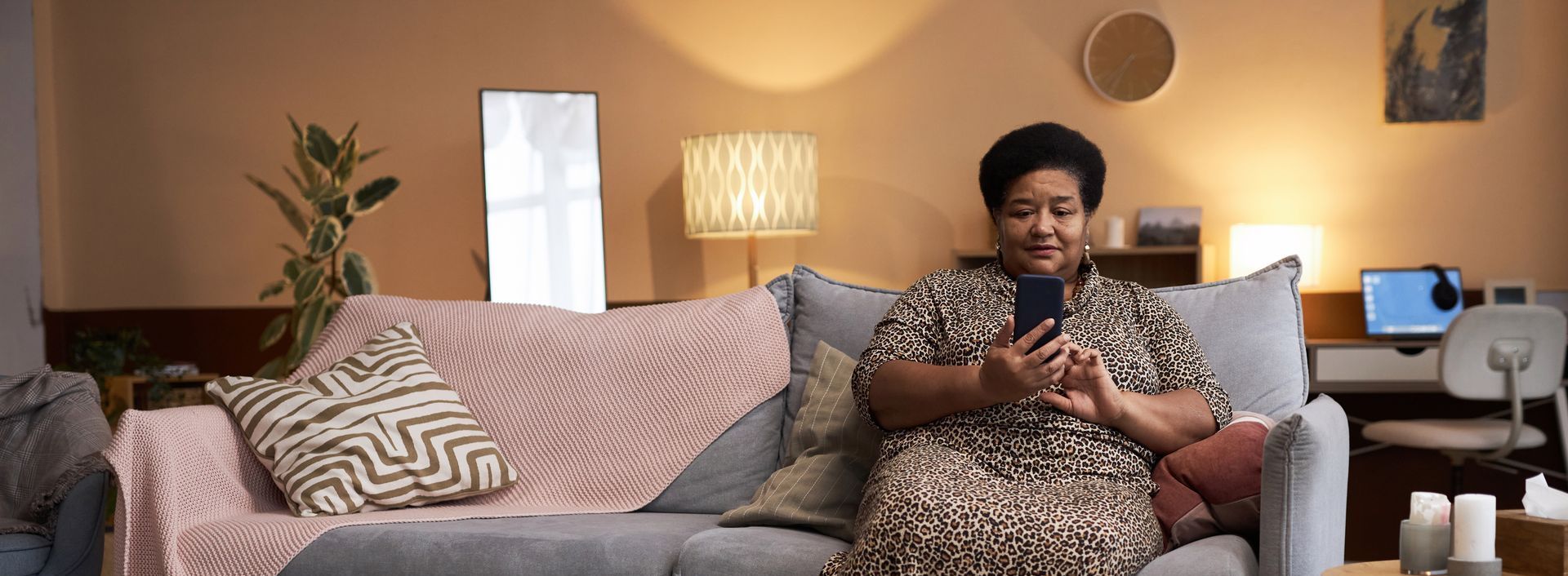 A senior woman sitting in a cosy living room using a smartphone