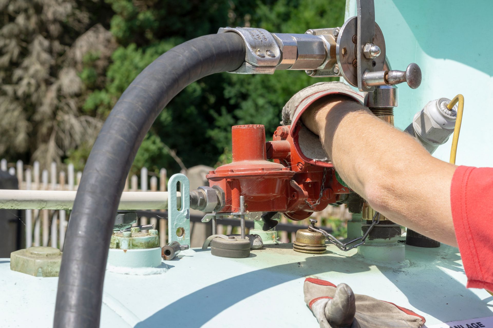 Close-up of a person filling a light blue domestic gas tank under the sun Close-up of a person filling a light blue domestic gas tank under the sun