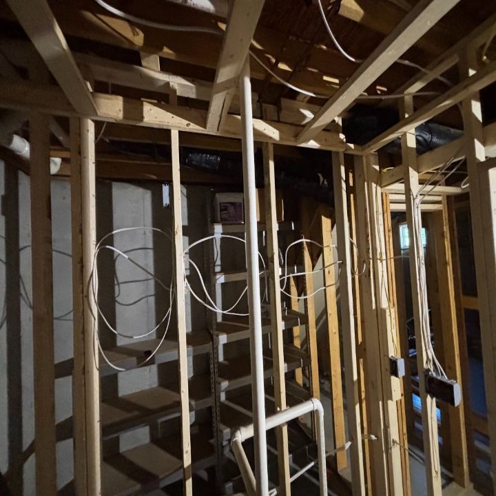 Exposed wooden framing inside a house under construction, with electrical wiring and open wall studs.