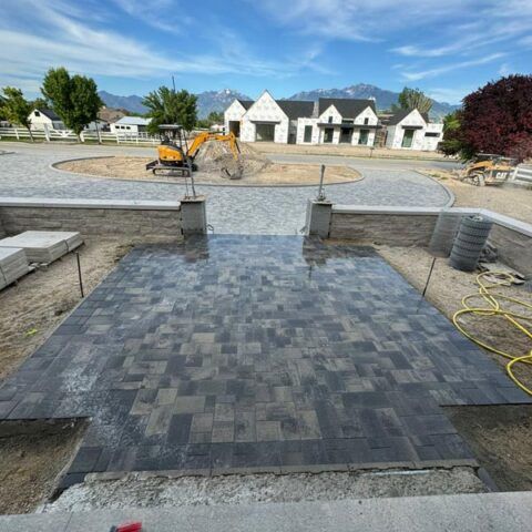 Freshly paved driveway with stone steps, construction equipment, and white houses in the background