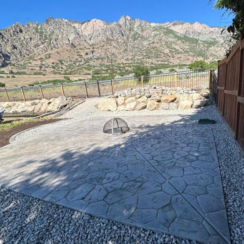 Stone patio with fire pit, gravel border, and mountain view under a clear blue sky