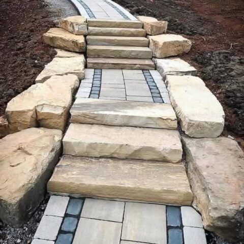 Stone steps and a tiled walkway forming a small path up a dirt slope outdoors