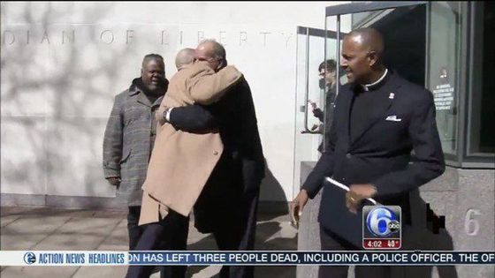 a man in a suit is hugging another man in front of a building with the number 6 on it