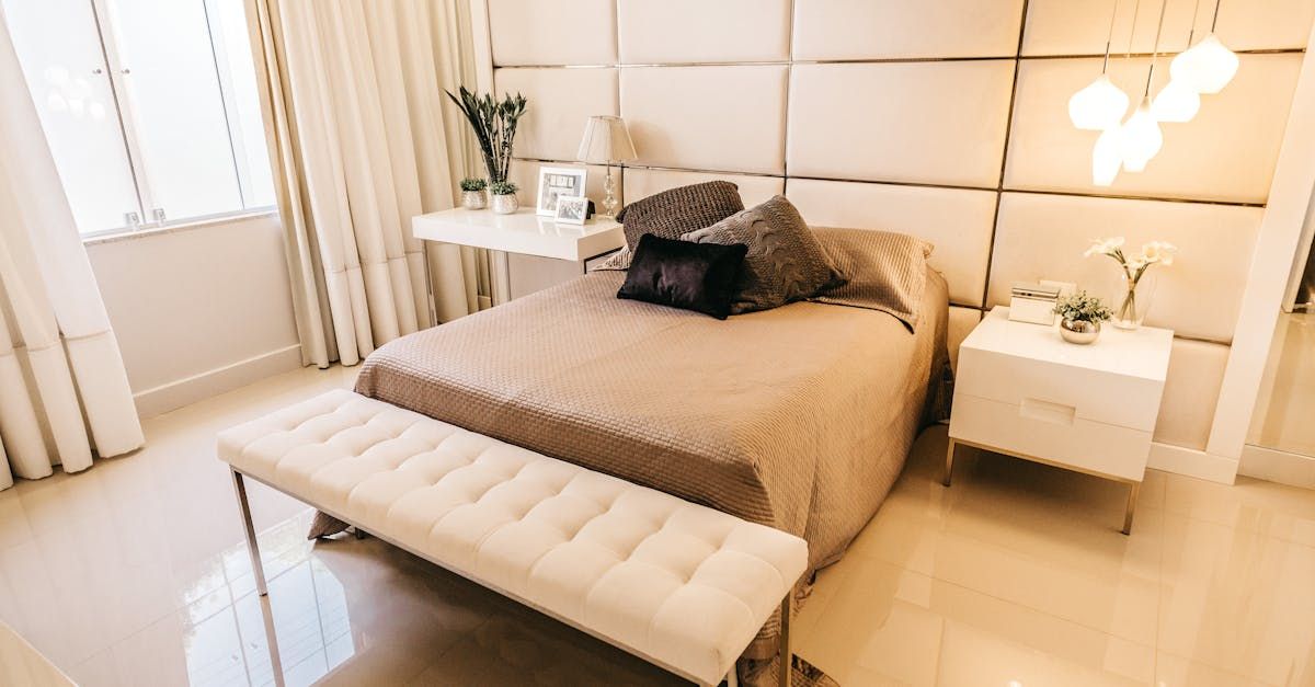 Una camera di hotel con letto, comodini e una panca.