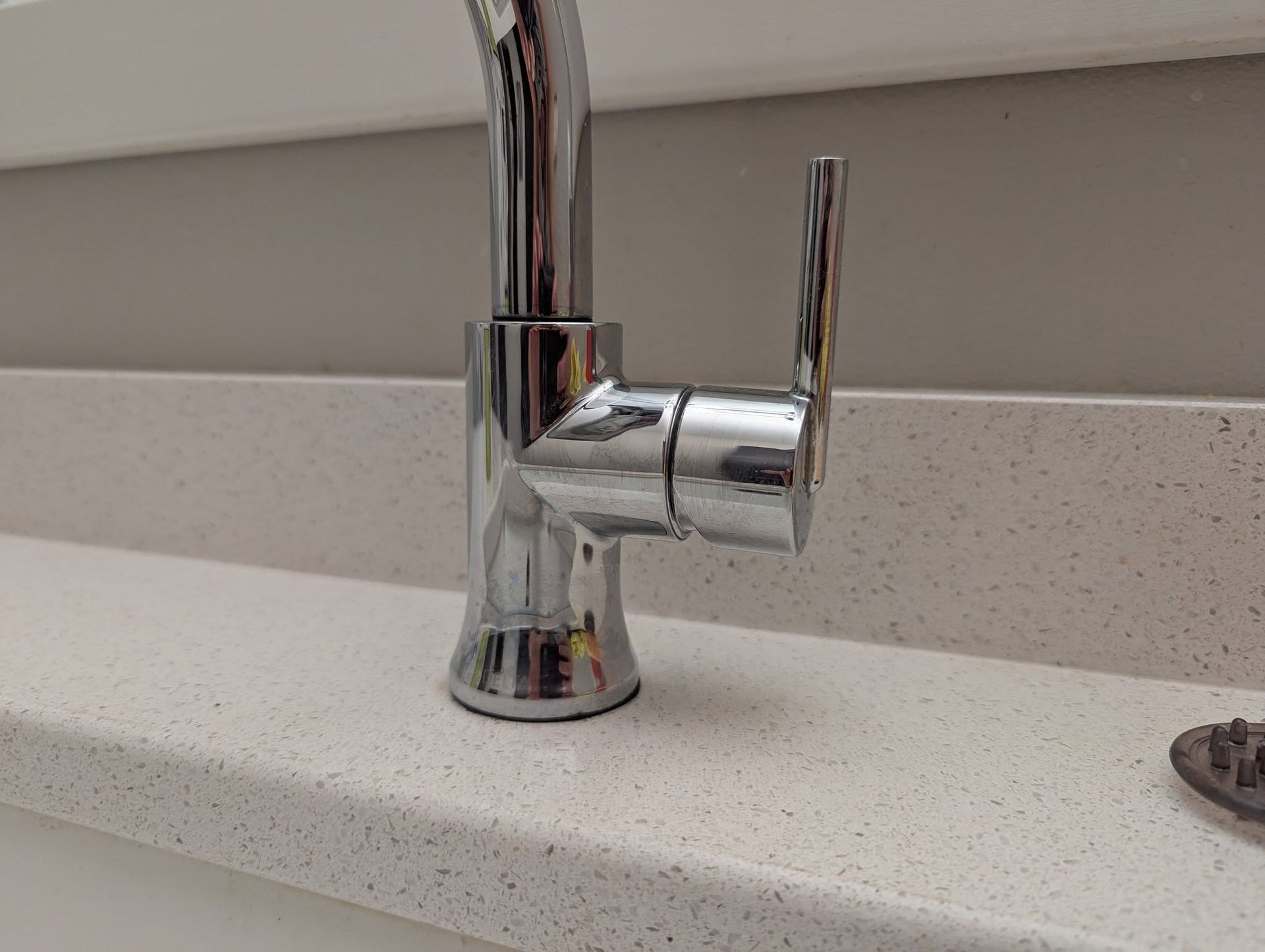 Chrome kitchen faucet on a white countertop with the handle in the closed position.
