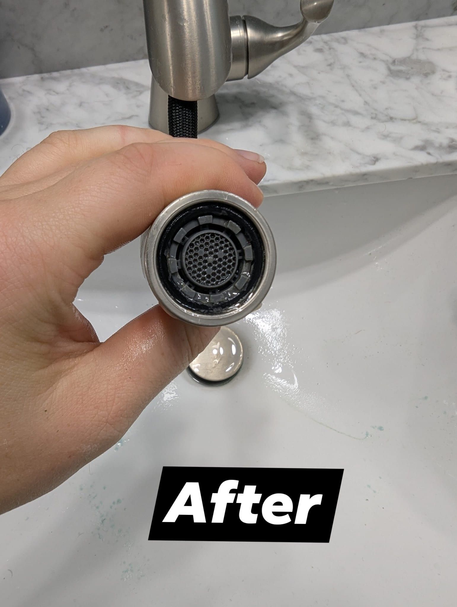 Hand holding a clean faucet aerator over a sink, with