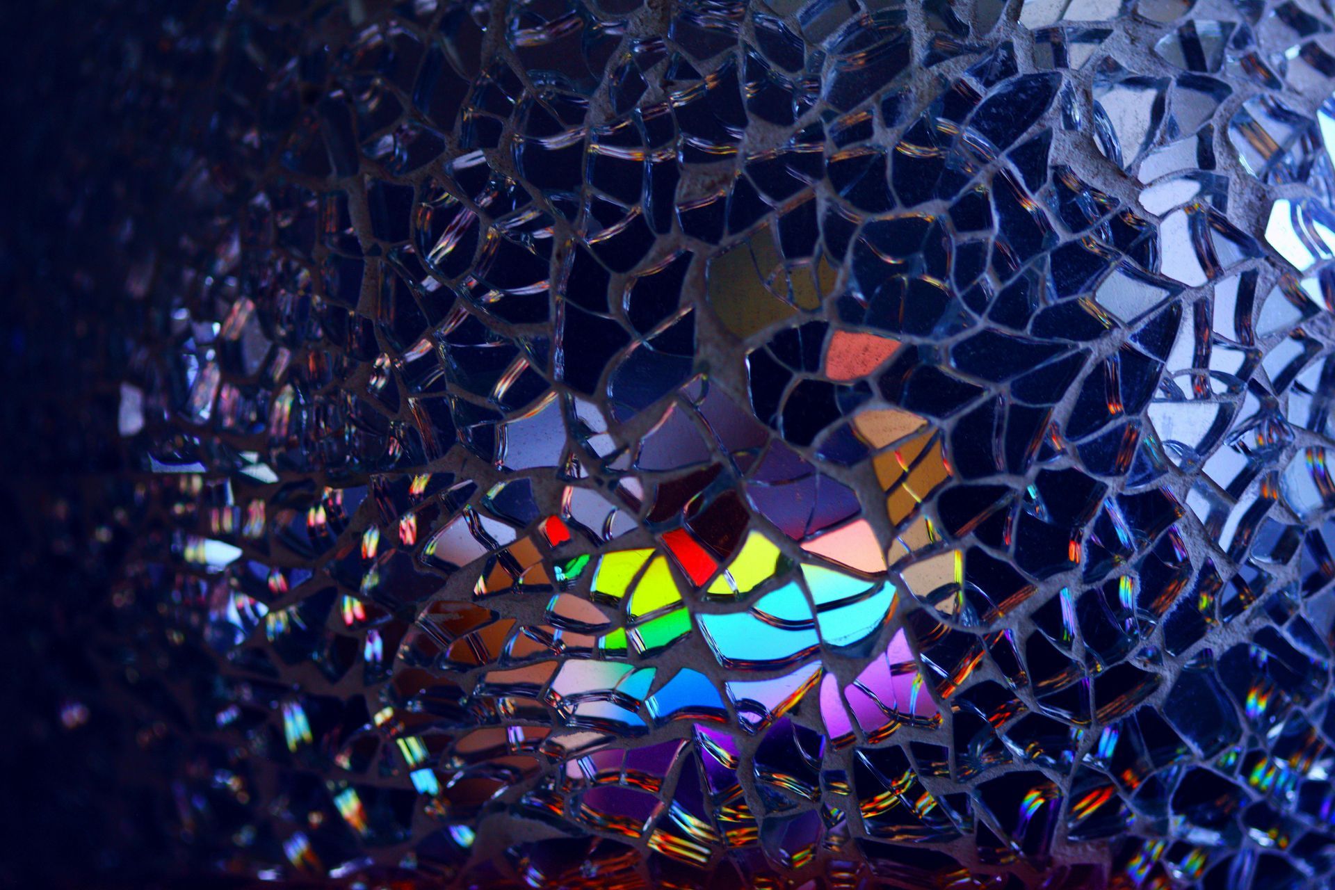 A rainbow is reflected in a broken glass window.
