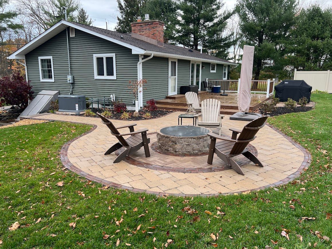 Backyard patio with fire pit, Adirondack chairs, and a house with green siding.