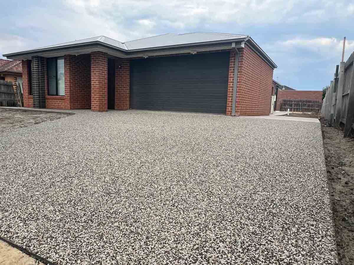 A brick house with a gravel driveway in front of it