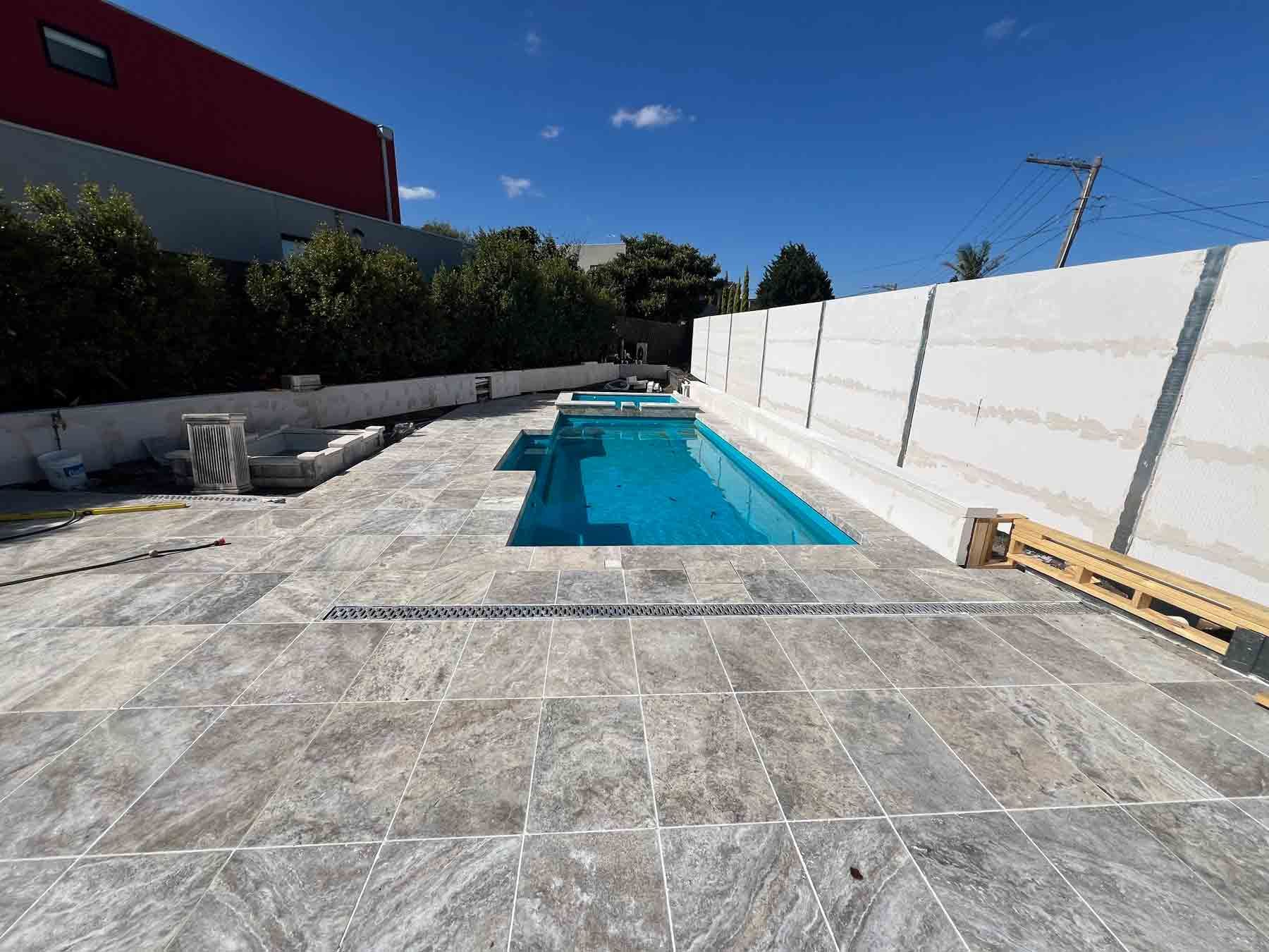 A large swimming pool is surrounded by a white fence