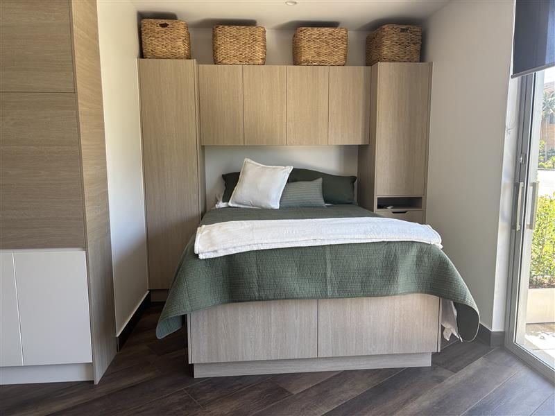 Modern bedroom with a bed and wicker storage baskets above — Piscopo Kitchens Plus In Forster, NSW