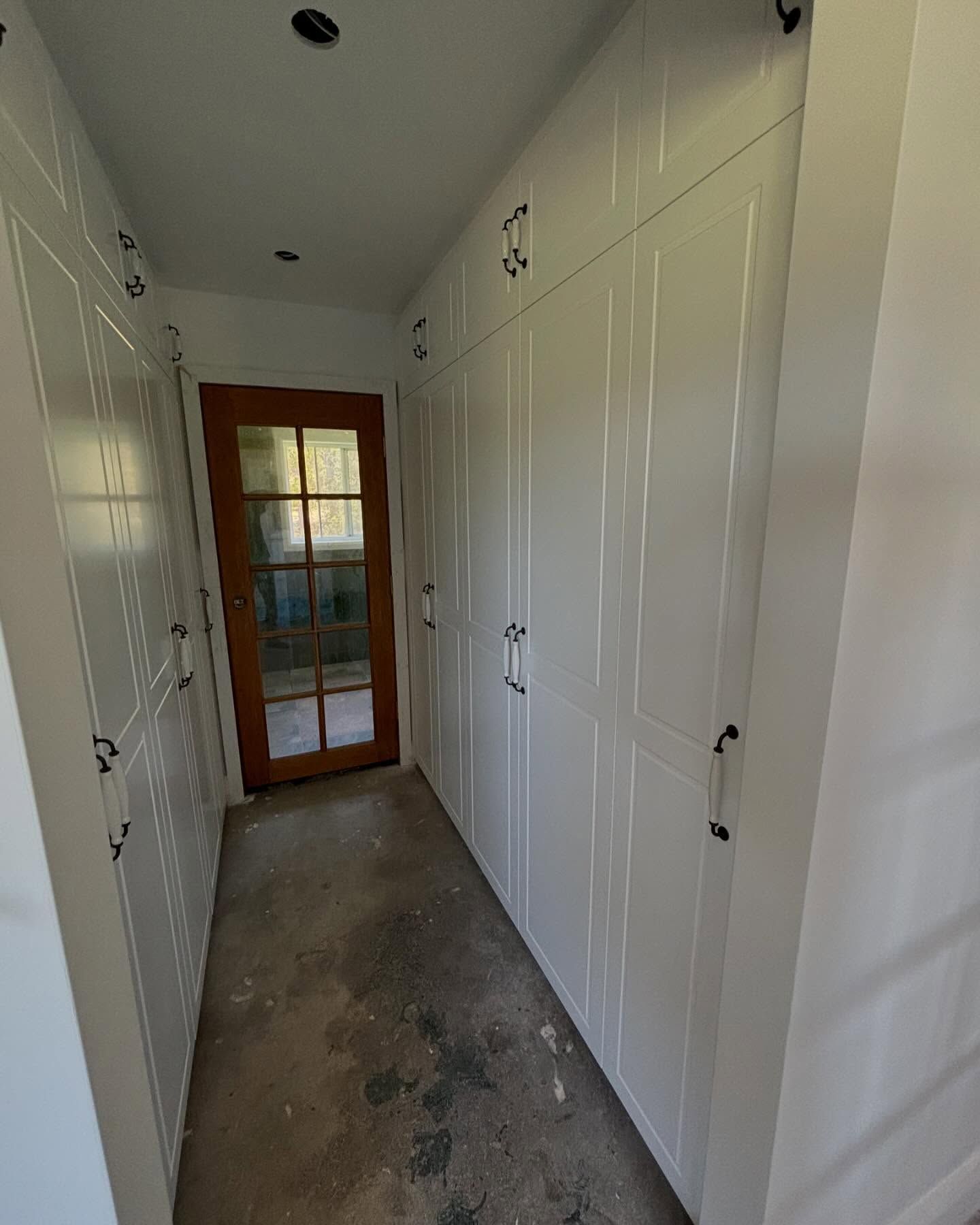 Narrow White Hallway With Built-in Closets, a Concrete Floor, and a Glass Door— Piscopo Kitchens Plus In Forster, NSW