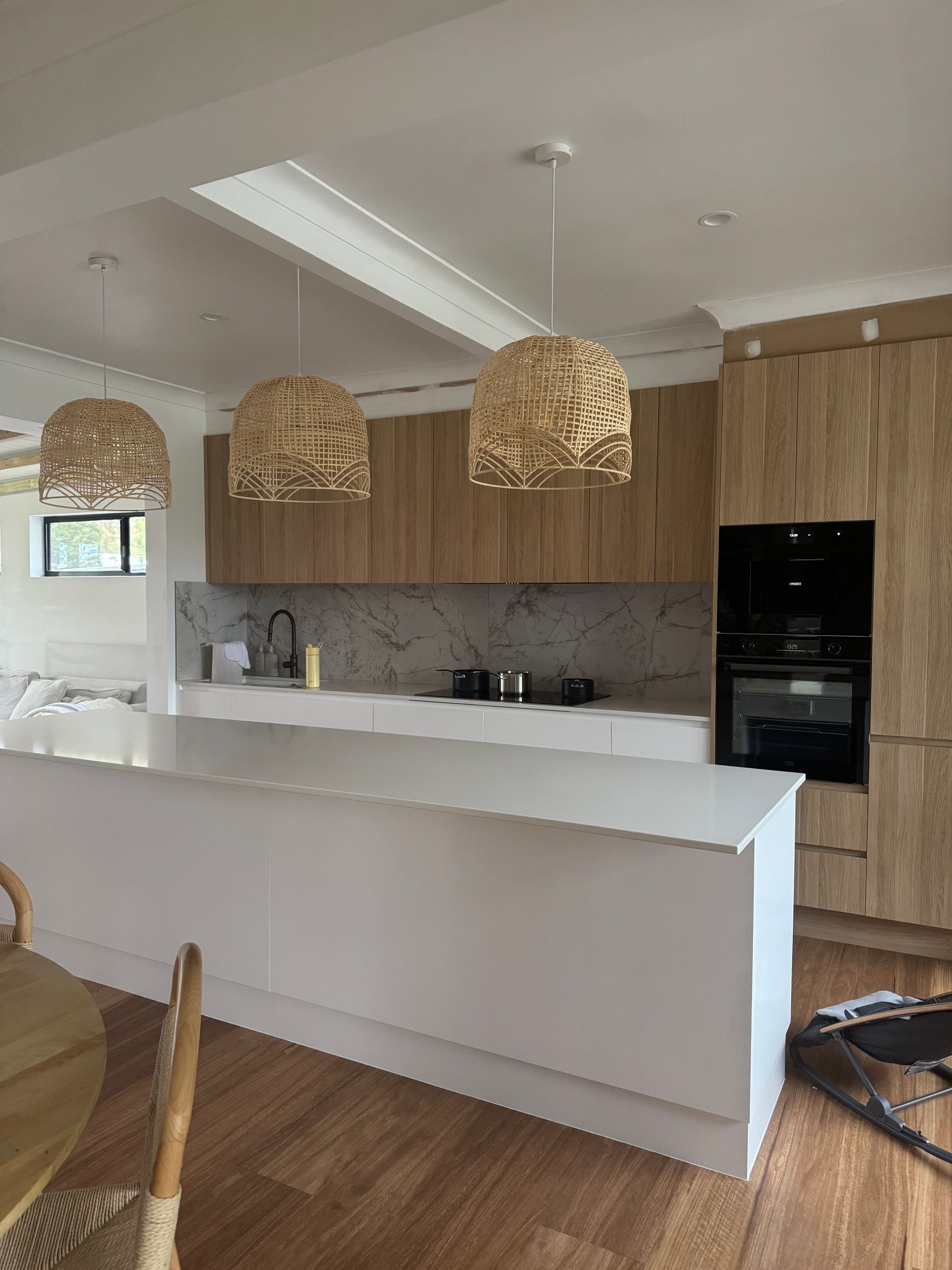 Kitchen island with drawers, microwave, and white countertop, set on wooden floor. — Piscopo Kitchens Plus In Forster, NSW