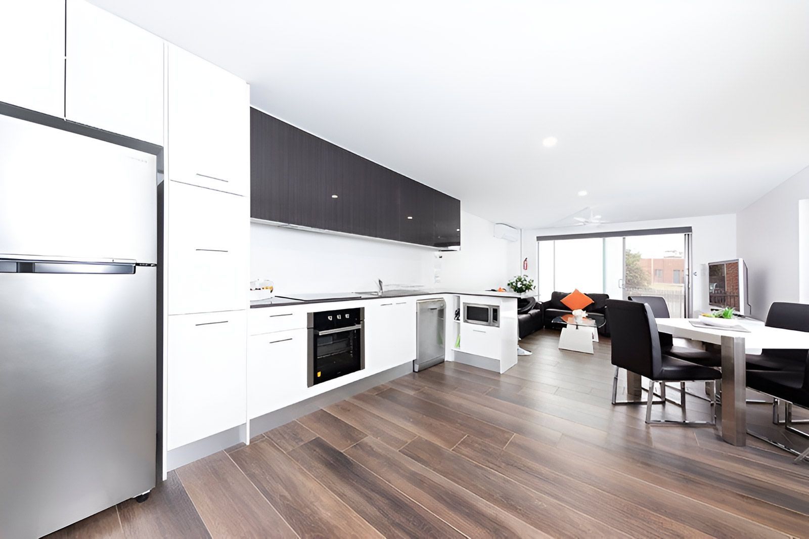 Kitchen and Living Area With Sleek White Cabinetry — Piscopo Kitchens Plus In Taree, NSW