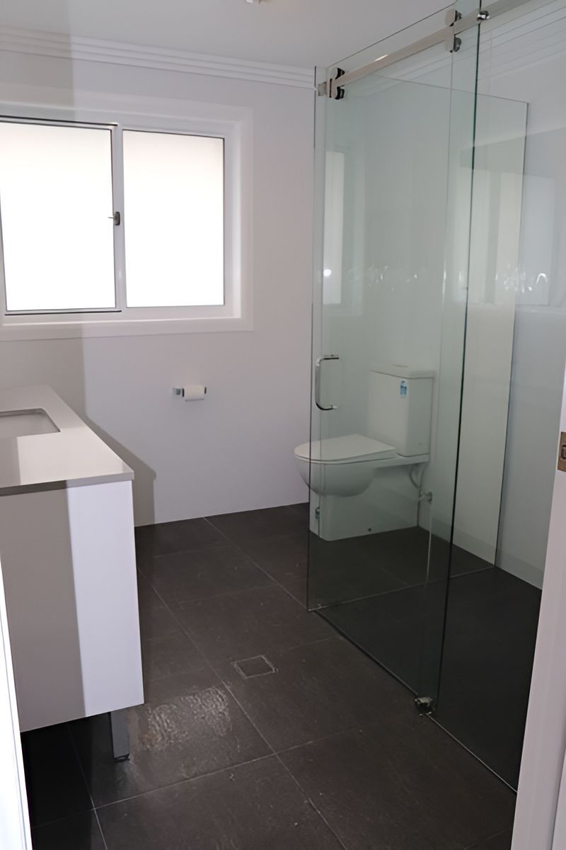 Bathroom With White Walls and Dark Floor Tiles — Piscopo Kitchens Plus In Wingham, NSW