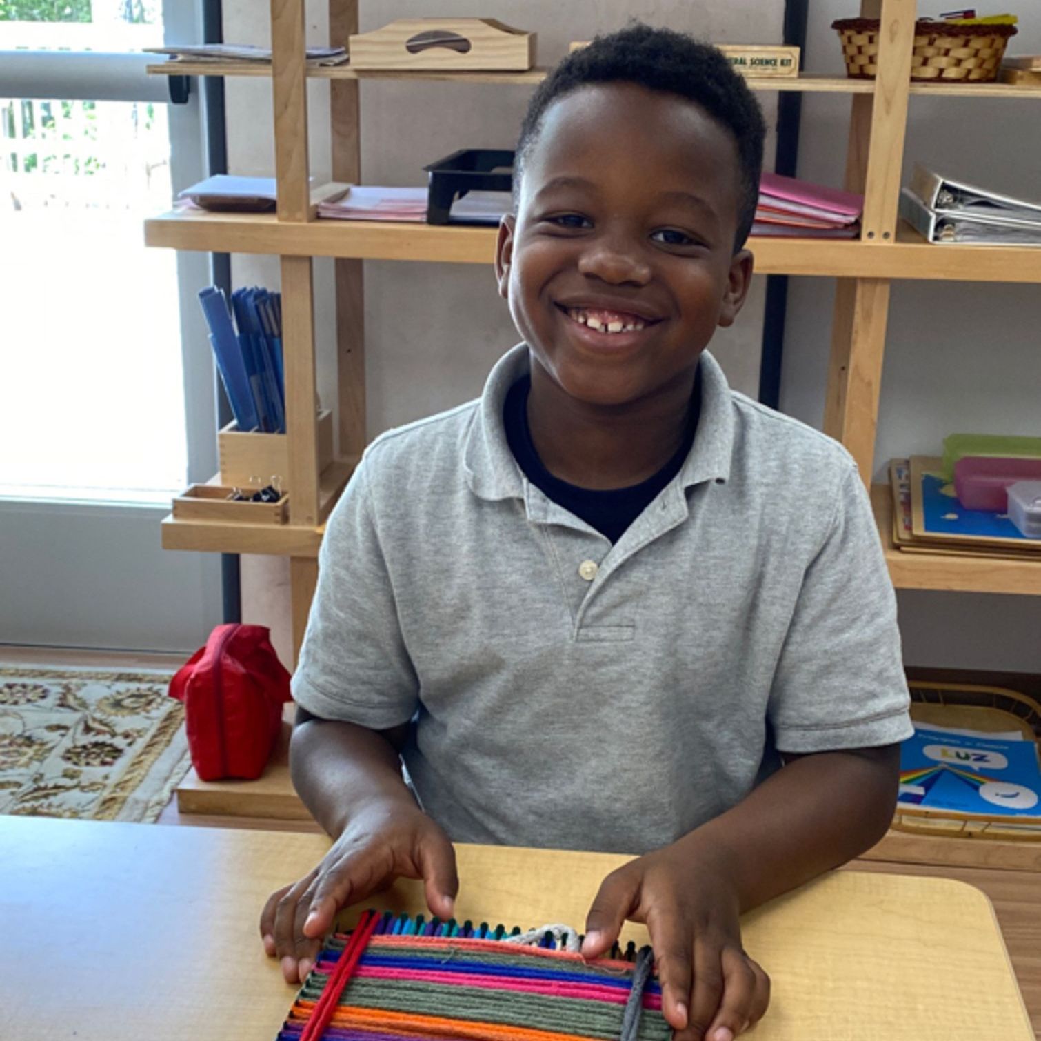 a Montessori child is smiling while sitting at a table