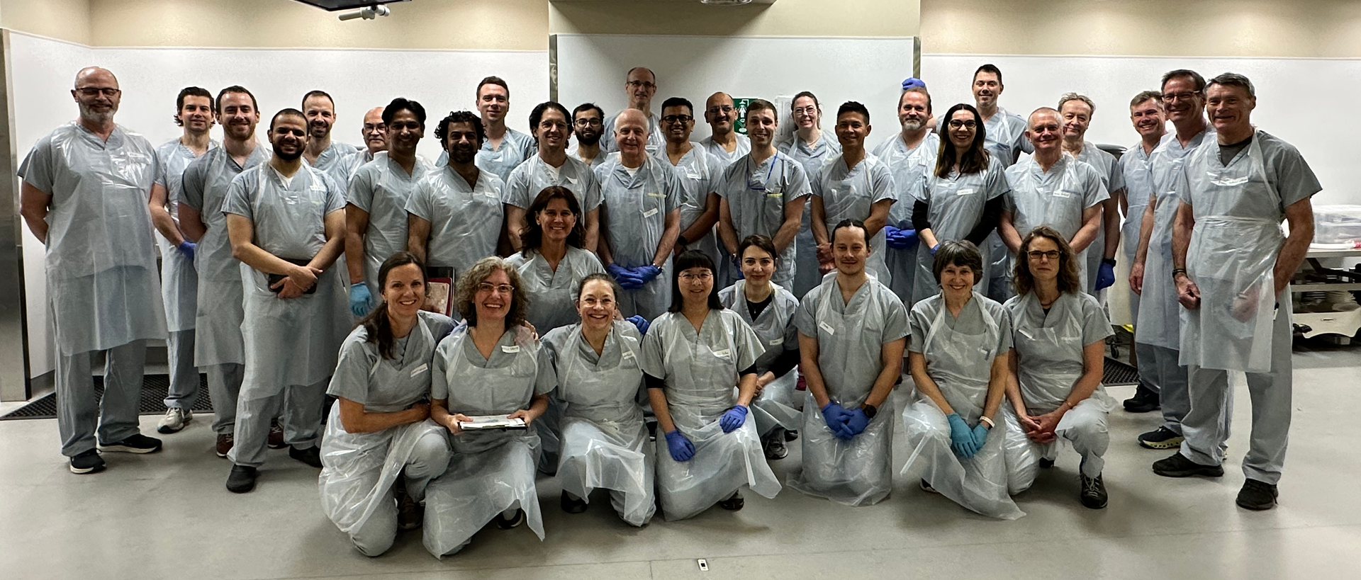 Group photo of staff in gray uniforms standing and kneeling in a bright indoor room