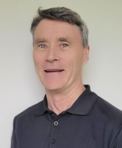 Portrait of a smiling man in a dark polo shirt against a light background