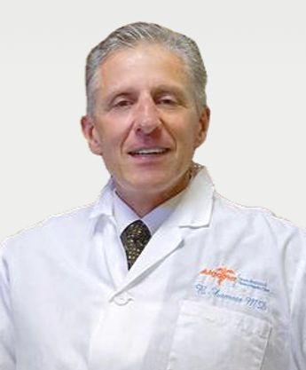 Doctor in white lab coat smiling against a plain background.