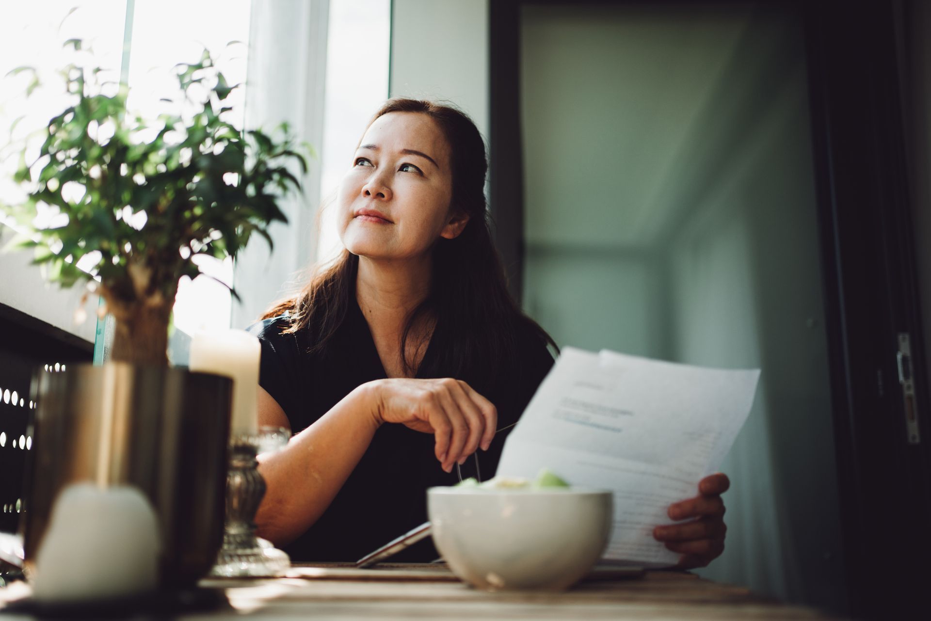 A woman is sitting at a table holding a piece of paper.