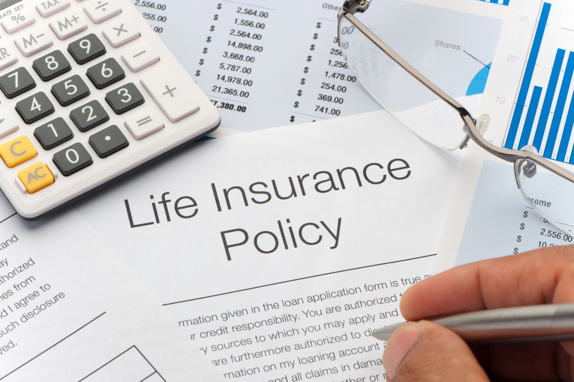 A person is writing on a life insurance policy with a pen.