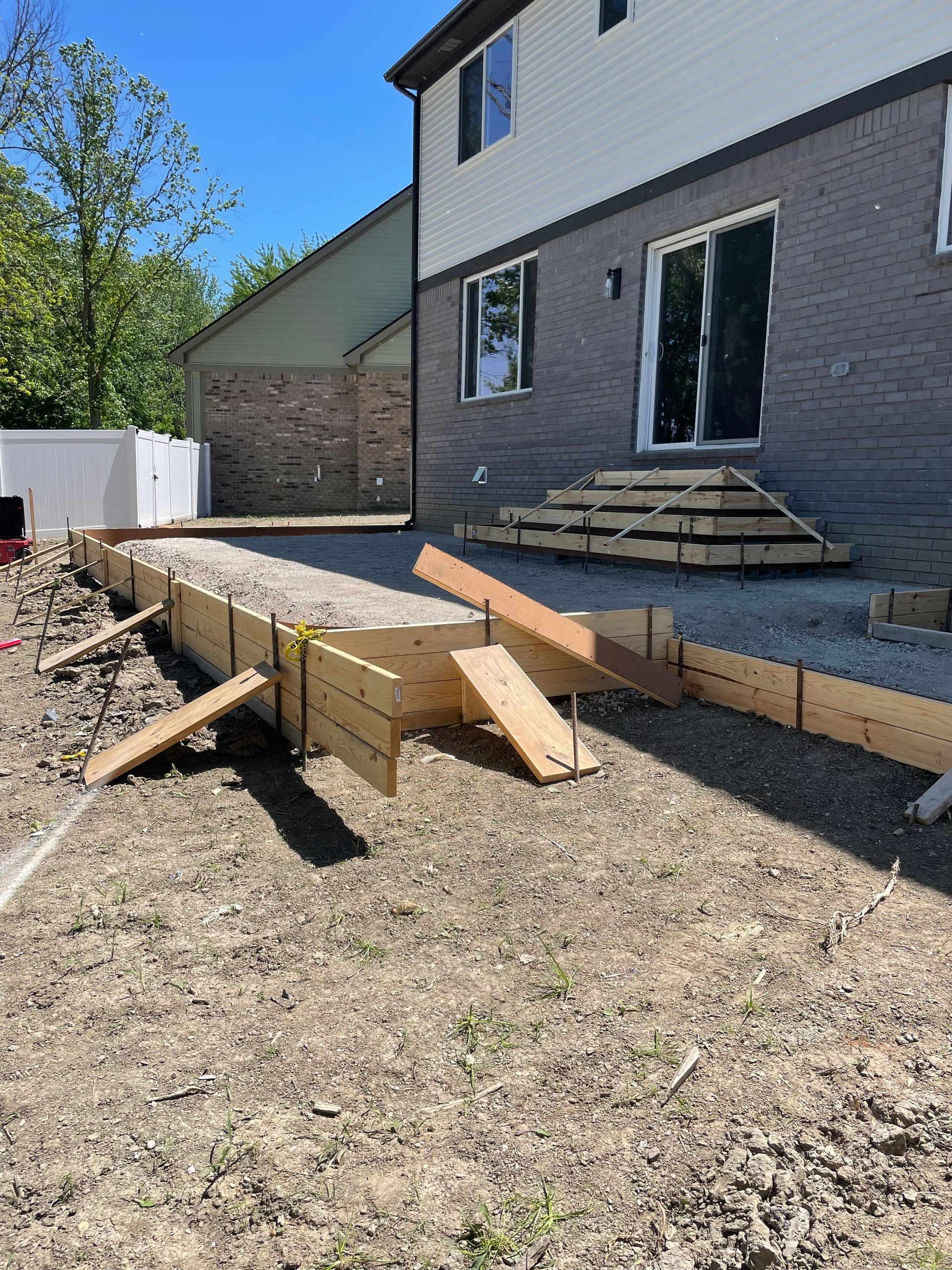 A concrete walkway is being built in front of a house.