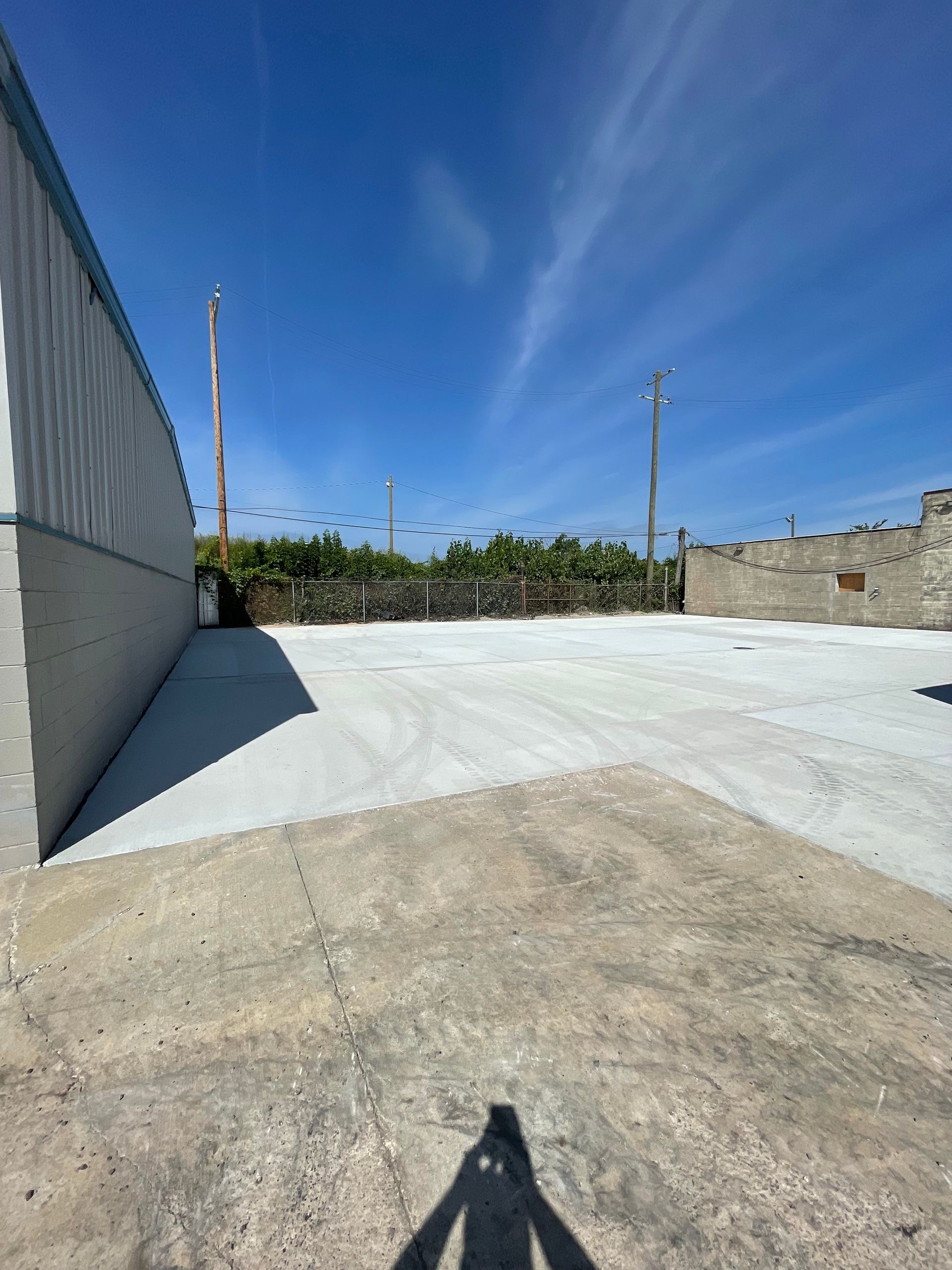 A shadow of a person is cast on the ground in a parking lot